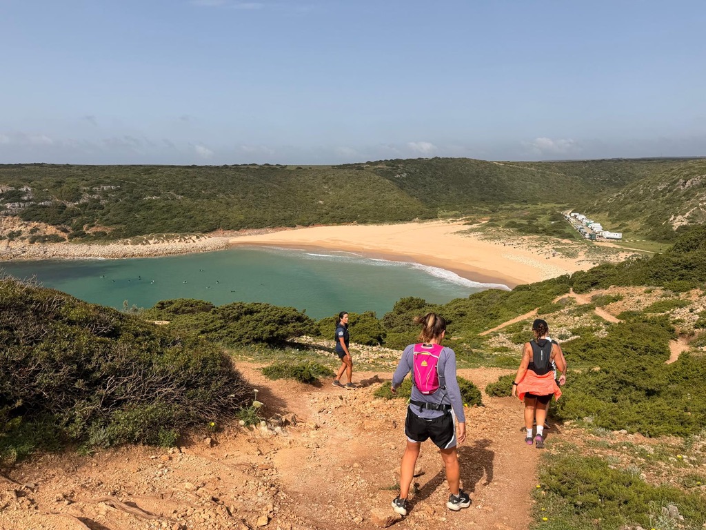 three women trail running on the Algarve cliffs with the coastline and ocean below