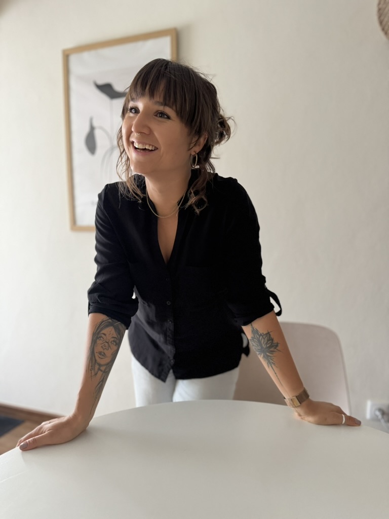 zuz, warm and laughing, leaning on a table
